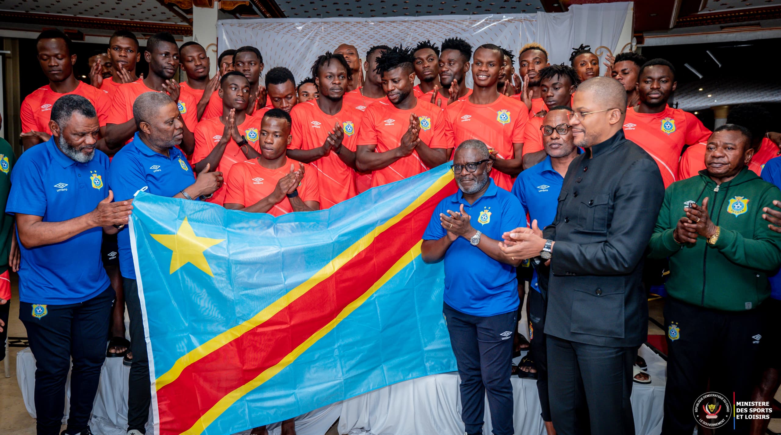 Le Ministre de sports Me Didier Budimbu à l'extrême droite remettant le drapeau congolais au sélectionneur des léopards Otis Ngoma